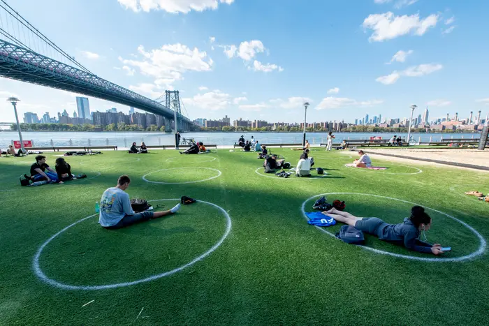 Visitors to Domino Park in Brooklyn sit in circles marked on the ground to help with "social distancing" with the Wiliamsburg Bridge.